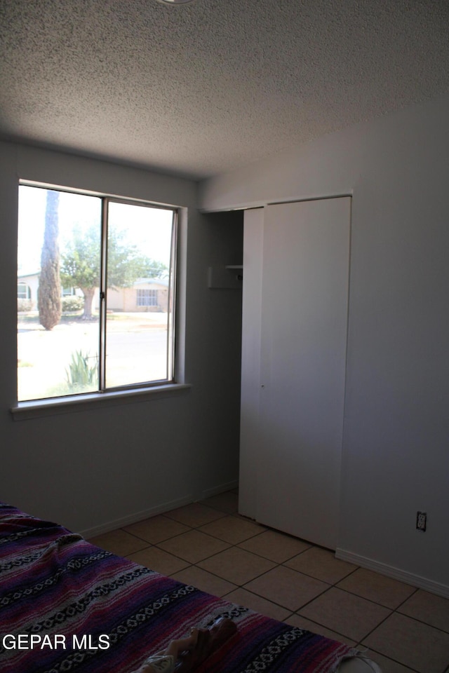 5124 Edmonton Ave, El Paso, TX 79924 - unfurnished bedroom with a textured ceiling, light tile patterned flooring, and a closet