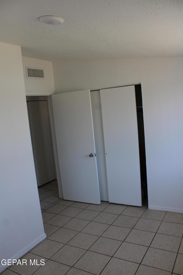 5124 Edmonton Ave, El Paso, TX 79924 - unfurnished bedroom with a textured ceiling, a closet, and light tile patterned flooring
