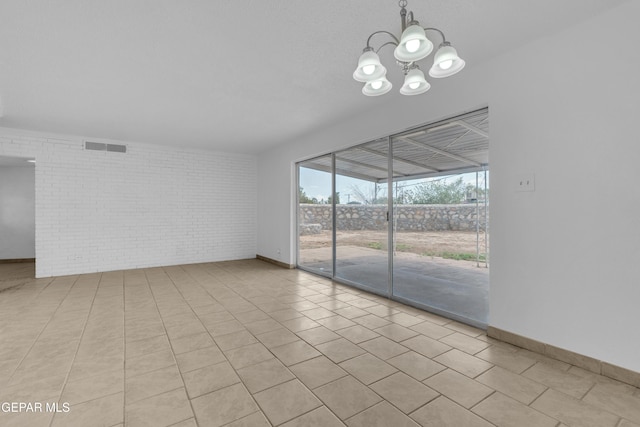 6033 Isabella Dr, El Paso, TX 79912 - unfurnished room featuring brick wall, a chandelier, and tile patterned flooring
