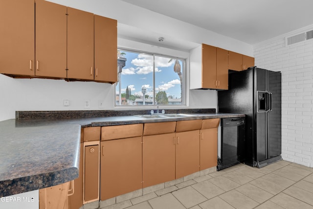6033 Isabella Dr, El Paso, TX 79912 - kitchen featuring black appliances, dark countertops, brick wall, and light tile patterned flooring