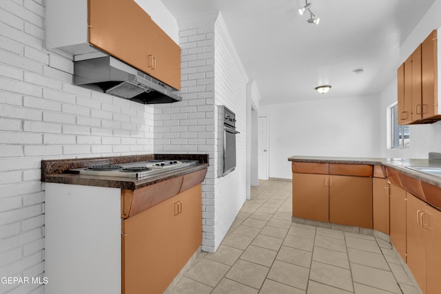 6033 Isabella Dr, El Paso, TX 79912 - kitchen with cooktop, light tile patterned floors, oven, a peninsula, and under cabinet range hood
