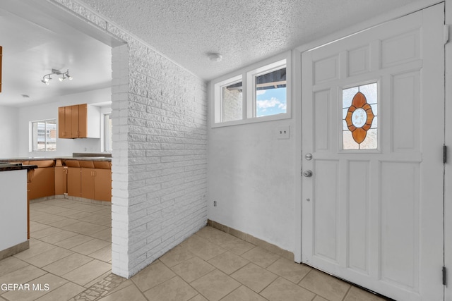 6033 Isabella Dr, El Paso, TX 79912 - entrance foyer featuring a textured ceiling, light tile patterned flooring, and brick wall