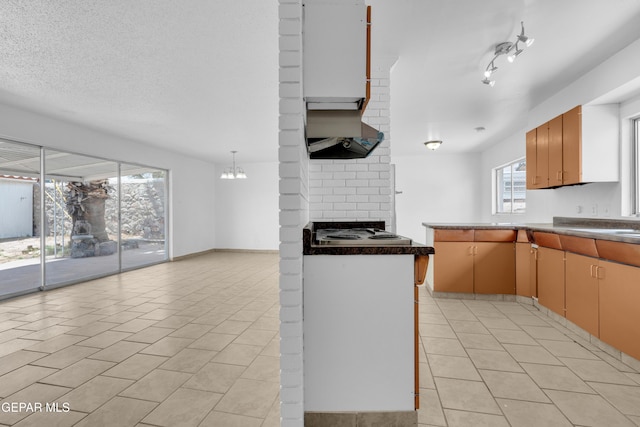 6033 Isabella Dr, El Paso, TX 79912 - kitchen with cooktop, range hood, light tile patterned flooring, and a brick fireplace