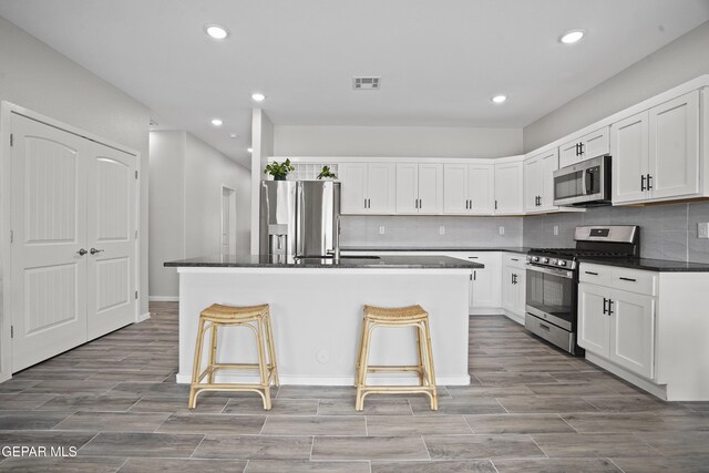 2308 Enchanted Quail, El Paso, TX 79911 - kitchen with stainless steel appliances, dark countertops, a kitchen island with sink, recessed lighting, and white cabinets