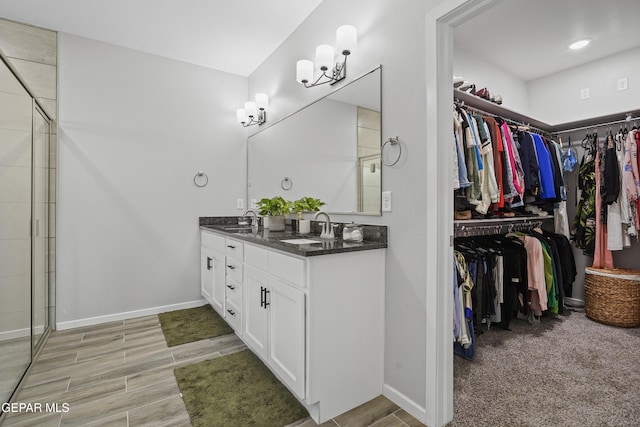 2308 Enchanted Quail, El Paso, TX 79911 - bathroom featuring double vanity, a spacious closet, a tile shower, and wood finished floors