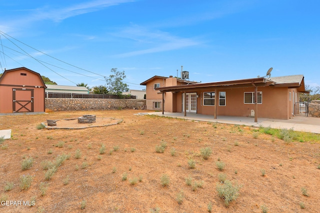 2912 Chaswood St, El Paso, TX 79935 - rear view of house featuring a fire pit, a patio, a fenced backyard, and a storage shed