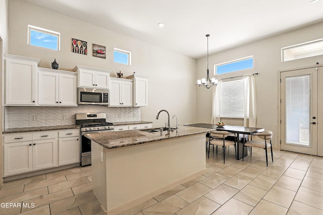 14512 Dominic Azcarate Dr, El Paso, TX 79938 - kitchen with appliances with stainless steel finishes, decorative backsplash, dark stone countertops, white cabinets, and a chandelier