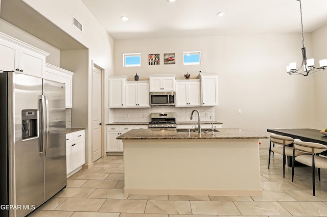 14512 Dominic Azcarate Dr, El Paso, TX 79938 - kitchen with stainless steel appliances, a chandelier, tasteful backsplash, white cabinetry, and dark stone countertops