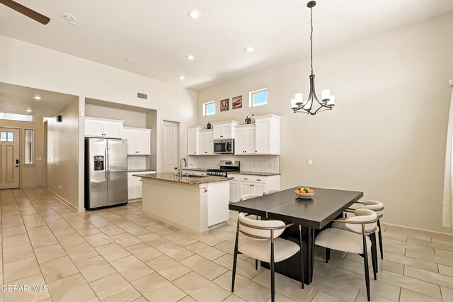 14512 Dominic Azcarate Dr, El Paso, TX 79938 - kitchen with stainless steel appliances, a chandelier, a center island with sink, backsplash, and light tile patterned floors