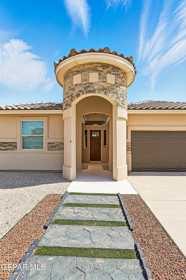 14512 Dominic Azcarate Dr, El Paso, TX 79938 - view of exterior entry featuring stucco siding, concrete driveway, a garage, a tile roof, and stone siding