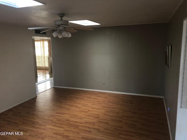 10309 Woodruff Ct, El Paso, TX 79925 - unfurnished room featuring a skylight, wood finished floors, a ceiling fan, and wooden walls