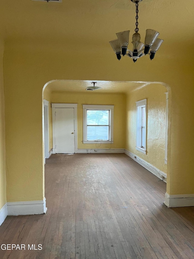 1118 N Laurel St, El Paso, TX 79902 - unfurnished dining area with a chandelier, arched walkways, and hardwood / wood-style flooring