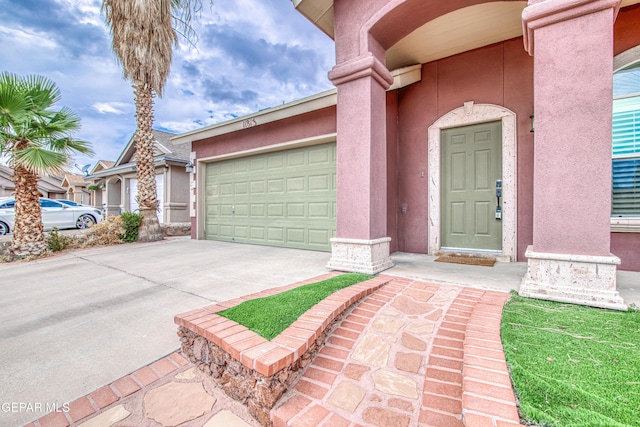 11813 Deer Grass Cir, El Paso, TX 79936 - view of exterior entry with concrete driveway, an attached garage, and stucco siding