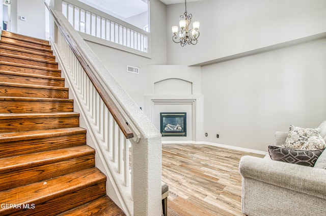 11813 Deer Grass Cir, El Paso, TX 79936 - stairway featuring wood finished floors, a towering ceiling, a chandelier, and a glass covered fireplace