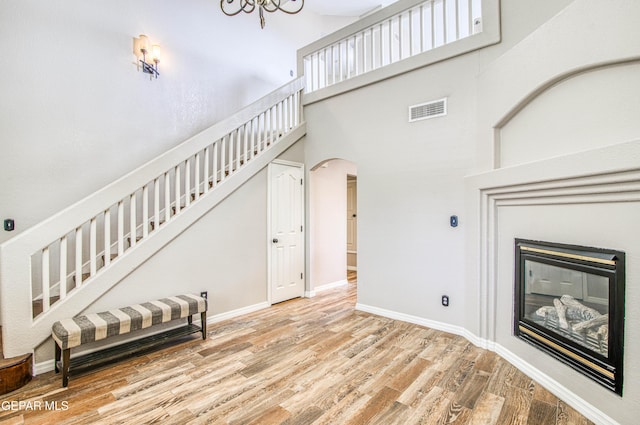 11813 Deer Grass Cir, El Paso, TX 79936 - stairs with wood finished floors, a towering ceiling, arched walkways, a glass covered fireplace, and a chandelier