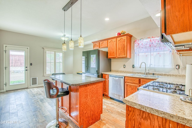 11813 Deer Grass Cir, El Paso, TX 79936 - kitchen with appliances with stainless steel finishes, light wood finished floors, a kitchen island, decorative light fixtures, and recessed lighting