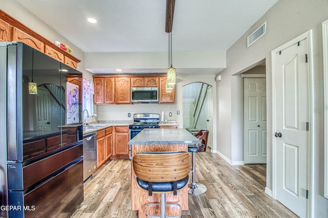 11813 Deer Grass Cir, El Paso, TX 79936 - kitchen with stainless steel appliances, light wood finished floors, arched walkways, a kitchen island, and decorative light fixtures