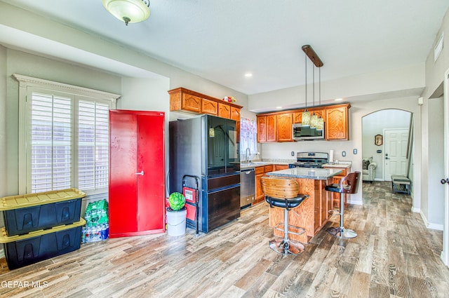 11813 Deer Grass Cir, El Paso, TX 79936 - kitchen featuring stainless steel appliances, arched walkways, a breakfast bar area, light wood-style floors, and recessed lighting