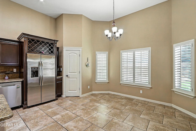 14552 Long Shadow Ave, El Paso, TX 79938 - kitchen with appliances with stainless steel finishes, a high ceiling, a chandelier, dark brown cabinetry, and plenty of natural light