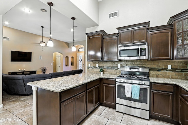 14552 Long Shadow Ave, El Paso, TX 79938 - kitchen with stainless steel appliances, arched walkways, a peninsula, light tile patterned floors, and dark brown cabinetry