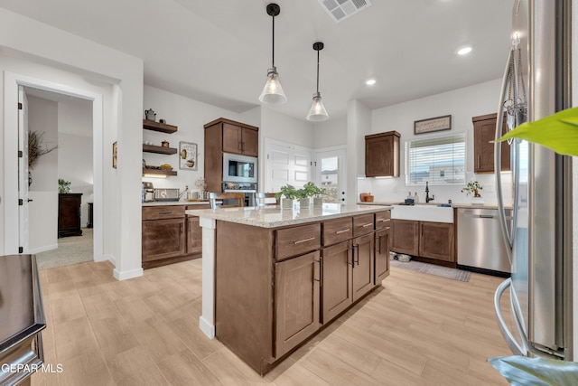 11157 Blazing Star Pl, El Paso, TX 79934 - kitchen with stainless steel appliances, open shelves, light wood-type flooring, decorative light fixtures, and a center island