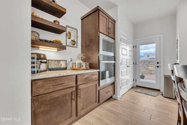 11157 Blazing Star Pl, El Paso, TX 79934 - kitchen with oven, built in microwave, light wood-style flooring, open shelves, and light stone counters