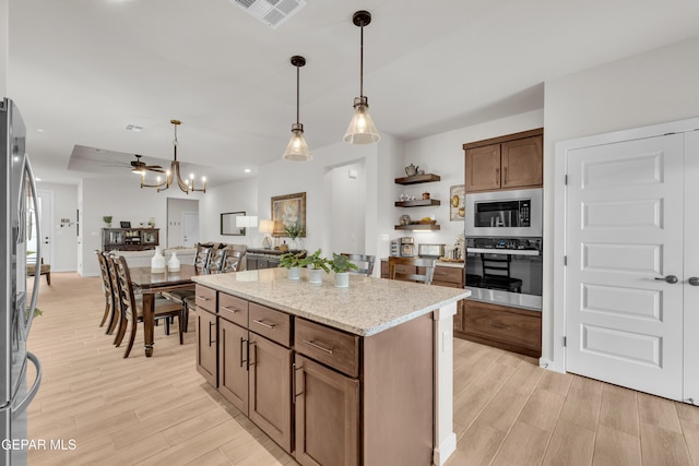 11157 Blazing Star Pl, El Paso, TX 79934 - kitchen featuring stainless steel appliances, light wood-style flooring, decorative light fixtures, a kitchen island, and light stone counters