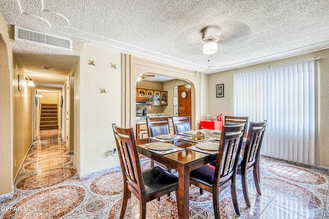 11581 Valle Verde Rd, Socorro, TX 79927 - dining room with arched walkways, a textured wall, a textured ceiling, stairs, and light tile patterned floors
