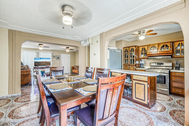 11581 Valle Verde Rd, Socorro, TX 79927 - dining room featuring ceiling fan, arched walkways, light tile patterned flooring, and a textured ceiling