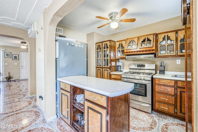 11581 Valle Verde Rd, Socorro, TX 79927 - kitchen featuring stainless steel gas stove, arched walkways, ceiling fan, light countertops, and a textured ceiling