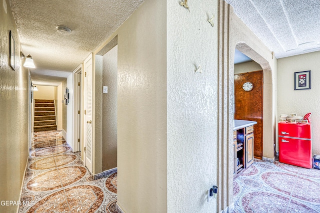 11581 Valle Verde Rd, Socorro, TX 79927 - hallway with a textured ceiling, a textured wall, arched walkways, tile patterned flooring, and stairway