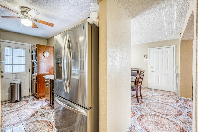 11581 Valle Verde Rd, Socorro, TX 79927 - kitchen with stainless steel fridge, a textured wall, a textured ceiling, light tile patterned flooring, and a ceiling fan