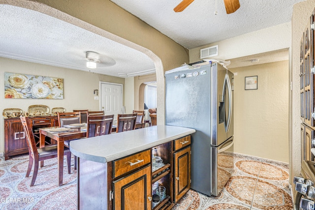 11581 Valle Verde Rd, Socorro, TX 79927 - kitchen featuring stainless steel refrigerator with ice dispenser, a textured ceiling, arched walkways, ceiling fan, and light tile patterned floors