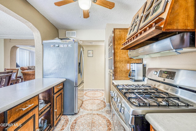 11581 Valle Verde Rd, Socorro, TX 79927 - kitchen featuring appliances with stainless steel finishes, arched walkways, a textured ceiling, ceiling fan, and brown cabinetry