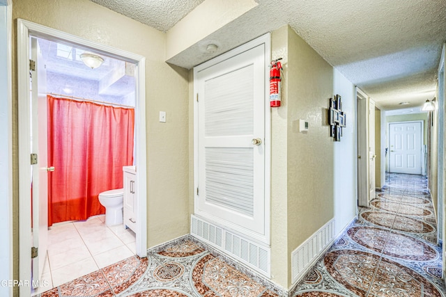 11581 Valle Verde Rd, Socorro, TX 79927 - hallway with a textured ceiling and light tile patterned flooring