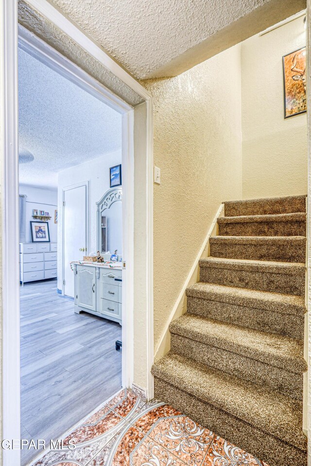 11581 Valle Verde Rd, Socorro, TX 79927 - stairs featuring a textured wall, a textured ceiling, and wood finished floors