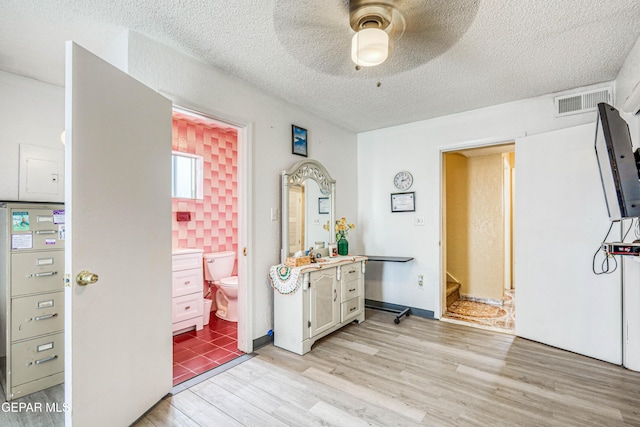 11581 Valle Verde Rd, Socorro, TX 79927 - bedroom featuring light wood-style floors, a textured ceiling, ensuite bathroom, and a ceiling fan