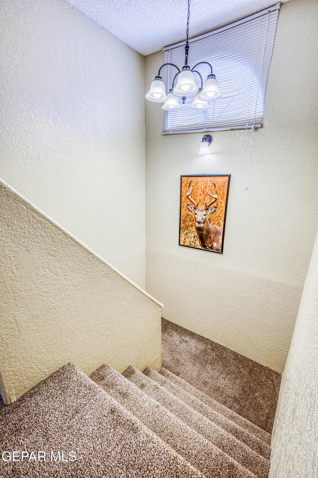 11581 Valle Verde Rd, Socorro, TX 79927 - staircase featuring a chandelier, carpet floors, a textured ceiling, and a textured wall