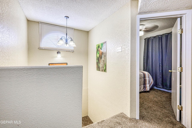 11581 Valle Verde Rd, Socorro, TX 79927 - hallway featuring a textured wall, carpet floors, a textured ceiling, and a chandelier