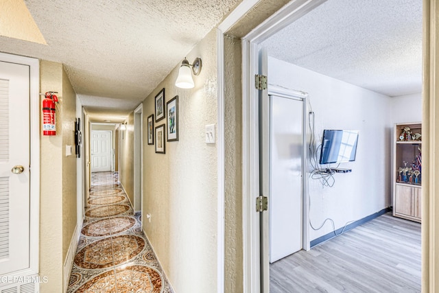 11581 Valle Verde Rd, Socorro, TX 79927 - corridor featuring a textured ceiling, light wood-type flooring, and a textured wall