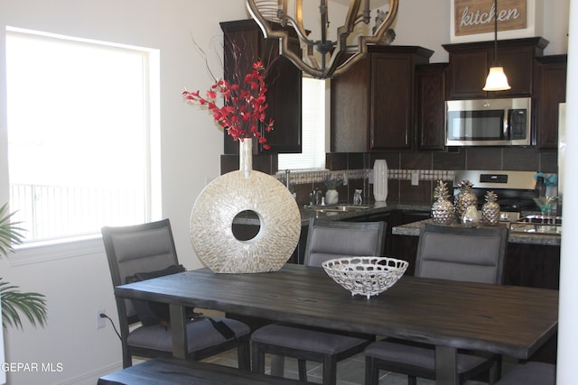 1374 Gusart Ave, El Paso, TX 79928 - kitchen featuring stainless steel appliances, dark brown cabinets, tasteful backsplash, dark countertops, and a chandelier