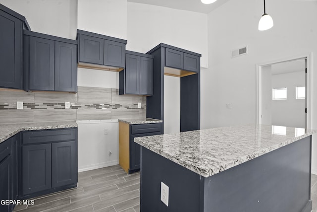2301 Tony Harper St, El Paso, TX 79938 - kitchen featuring tasteful backsplash, wood finish floors, light stone counters, a high ceiling, and pendant lighting