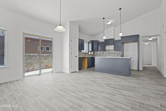 2301 Tony Harper St, El Paso, TX 79938 - kitchen with light wood-type flooring, decorative light fixtures, open floor plan, high vaulted ceiling, and a kitchen island