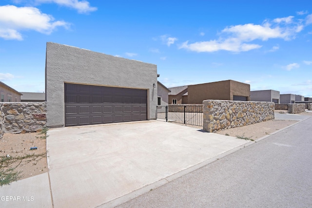 2301 Tony Harper St, El Paso, TX 79938 - view of side of home with a garage, stucco siding, and concrete driveway