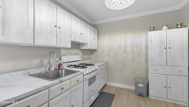 2123 Magoffin Ave, El Paso, TX 79901 - kitchen with white gas range oven, light wood-type flooring, white cabinets, crown molding, and a chandelier