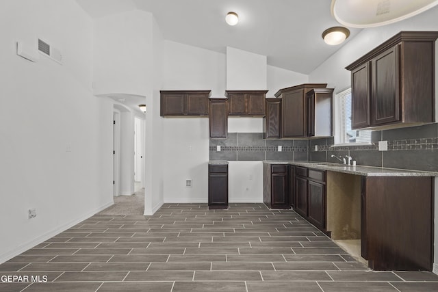 14325 Toby Davis Dr, Horizon City, TX 79928 - kitchen with tasteful backsplash, dark brown cabinets, dark wood-style floors, arched walkways, and high vaulted ceiling