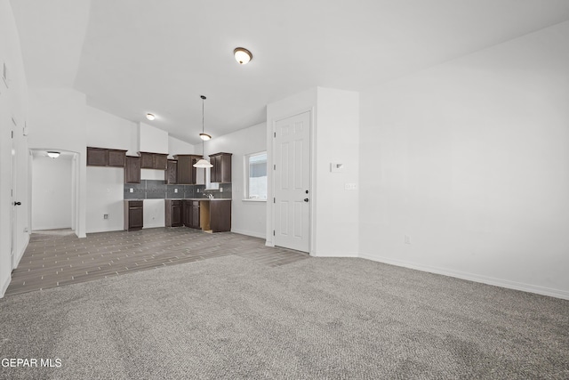 14325 Toby Davis Dr, Horizon City, TX 79928 - kitchen with light carpet, dark brown cabinets, tasteful backsplash, lofted ceiling, and pendant lighting