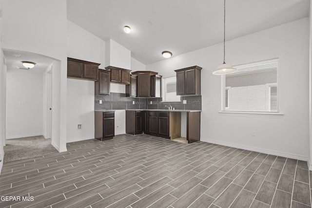 14325 Toby Davis Dr, Horizon City, TX 79928 - kitchen with dark brown cabinetry, backsplash, wood finished floors, hanging light fixtures, and light countertops