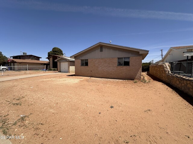 5513 Fairbanks Dr, El Paso, TX 79924 - back of house featuring brick siding, concrete driveway, a garage, and an outbuilding