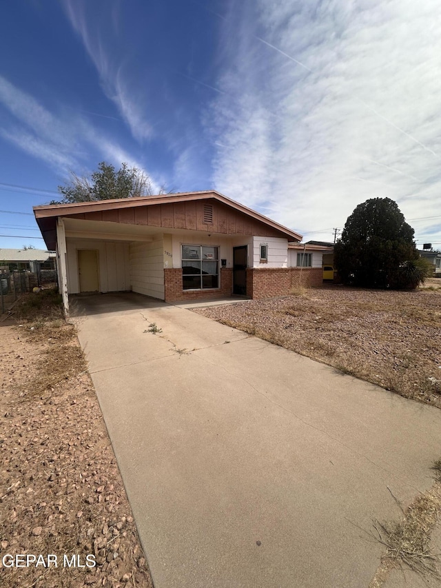 5829 Nike Ln, El Paso, TX 79924 - ranch-style house with brick siding, concrete driveway, a carport, and board and batten siding